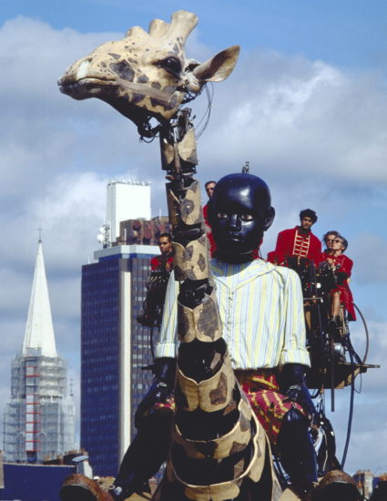 Le Petit Géant est sur le dos de la grande Girafe. Derrière eux la tour de Bretagne, à Nantes
