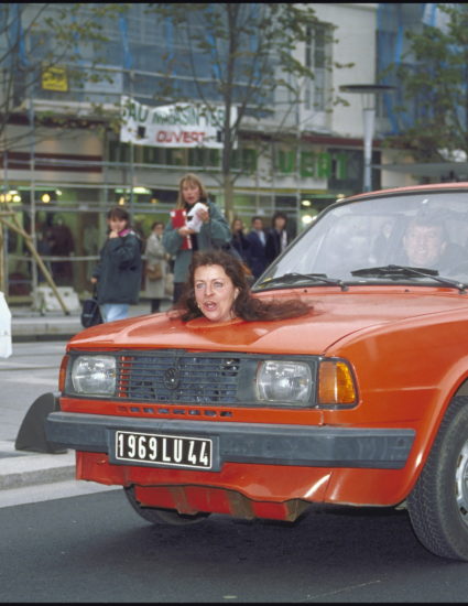 Une tête de femme sort du capot d'une voiture