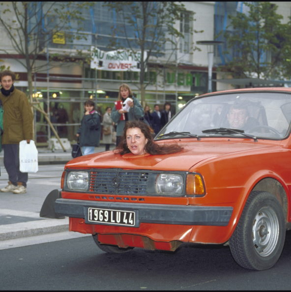 Une tête de femme sort du capot d'une voiture