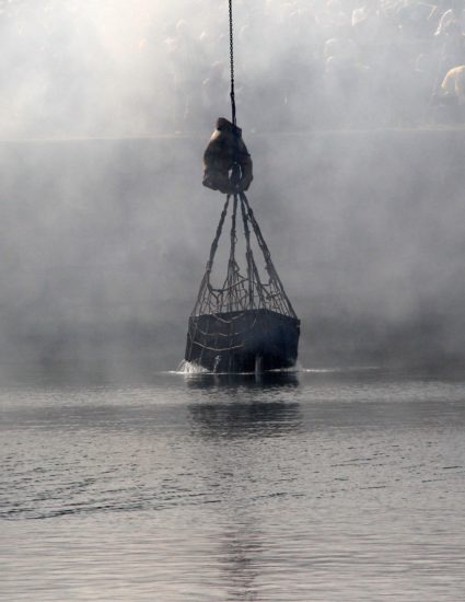 La Main du Scaphandrier sort de l'eau. Elle tient un filet dans lequel est emprisonnée une malle...