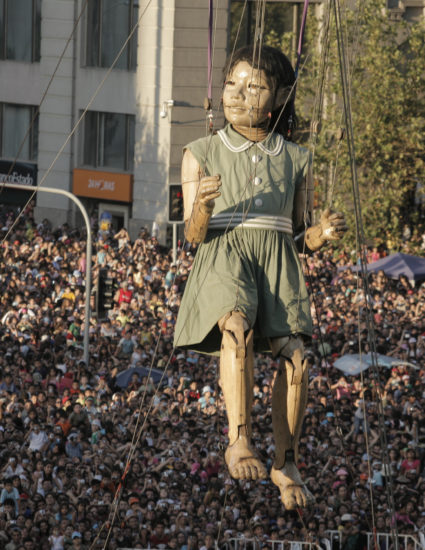 La Petite Géante flotte dans les airs, derrière on aperçoit la foule